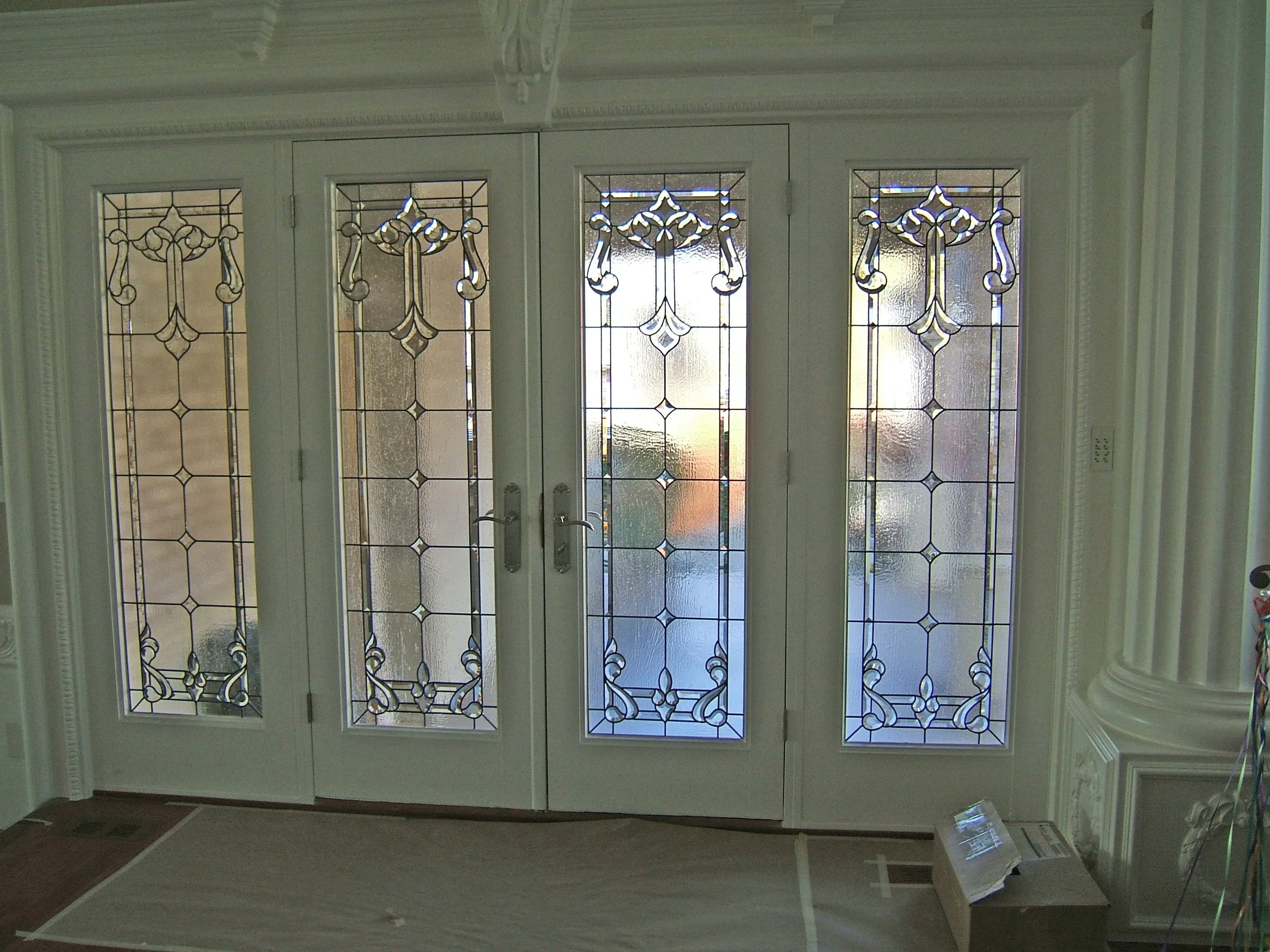 Four-panel French doors with custom leaded glass geometric and scrollwork patterns