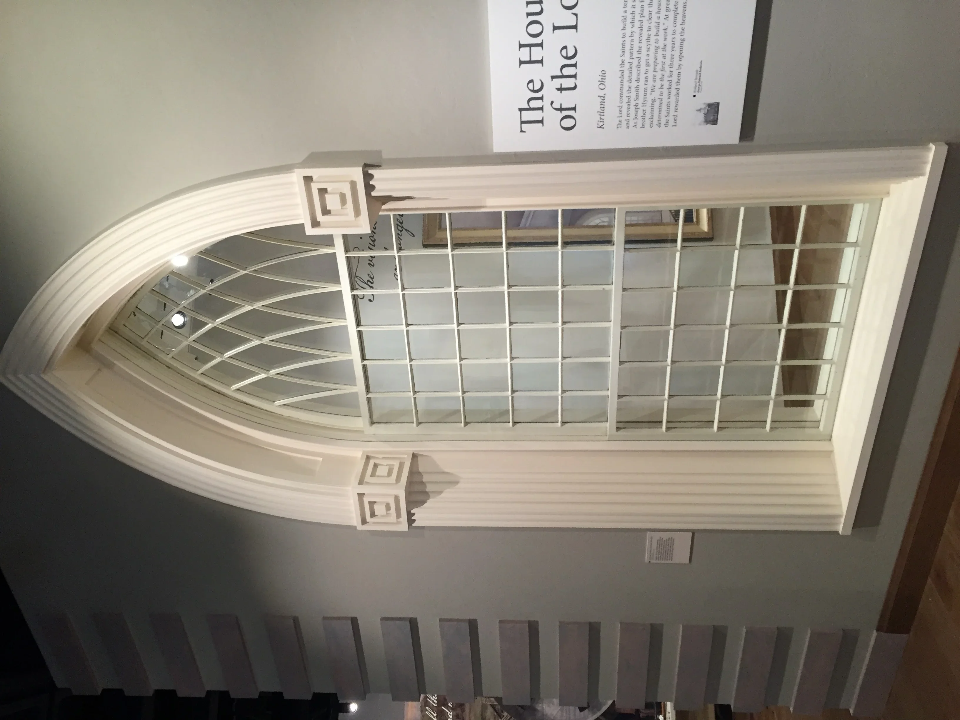 Cream-framed arched glass door with geometric grille pattern and decorative hardware