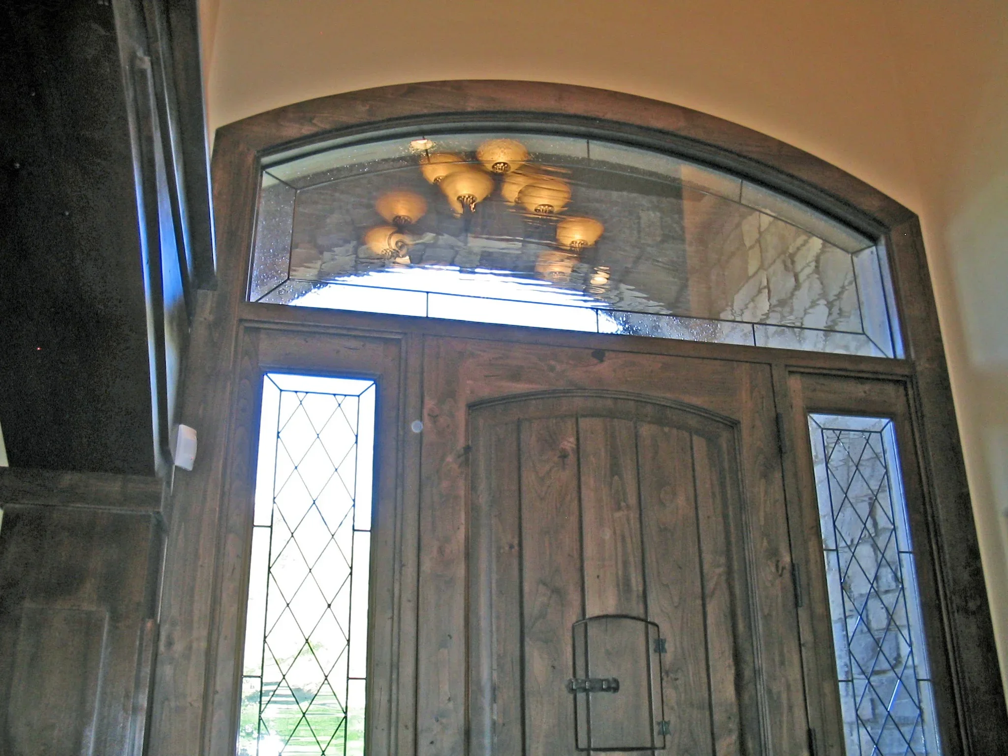 Arched entryway with beveled glass transom and diamond-patterned sidelights in wood frame