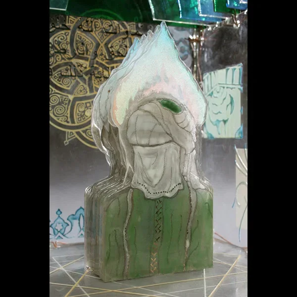 Sculptural glass head with white hair and green robe, detailed facial features and ornamental carving