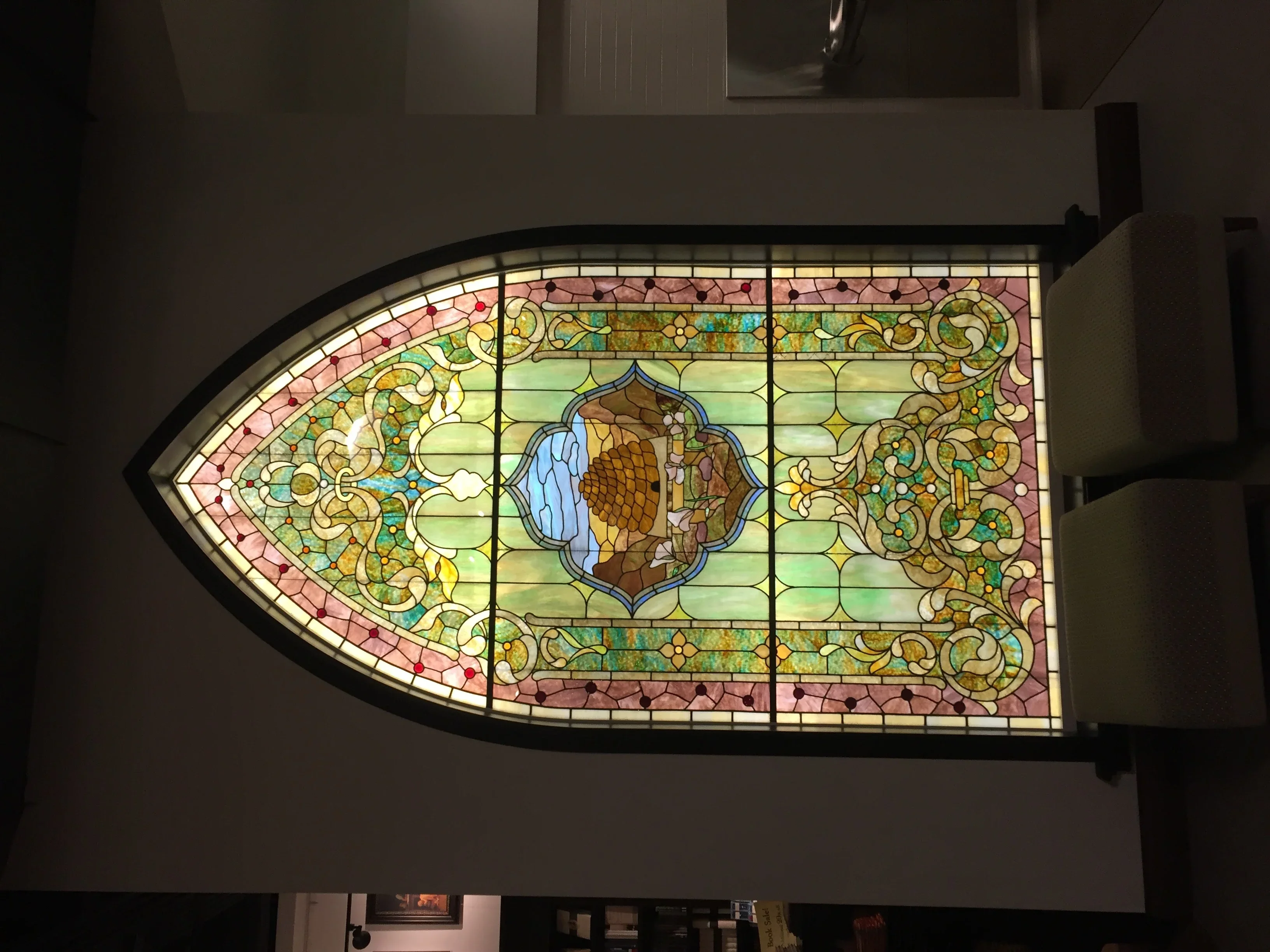 Illuminated stained glass window with ornate floral patterns and central medallion design