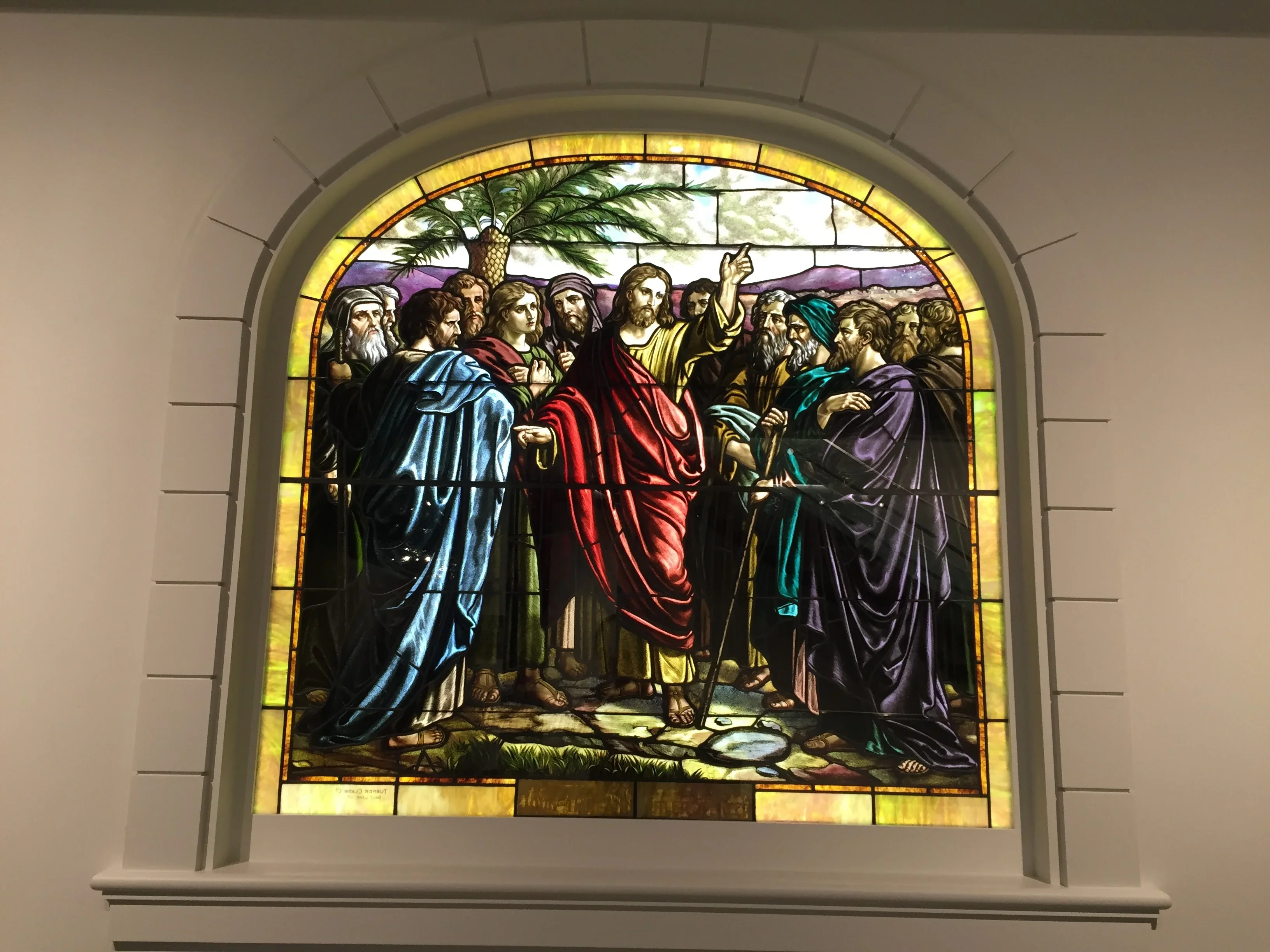 Arched stained glass window with religious figures in colored glass and lead framework