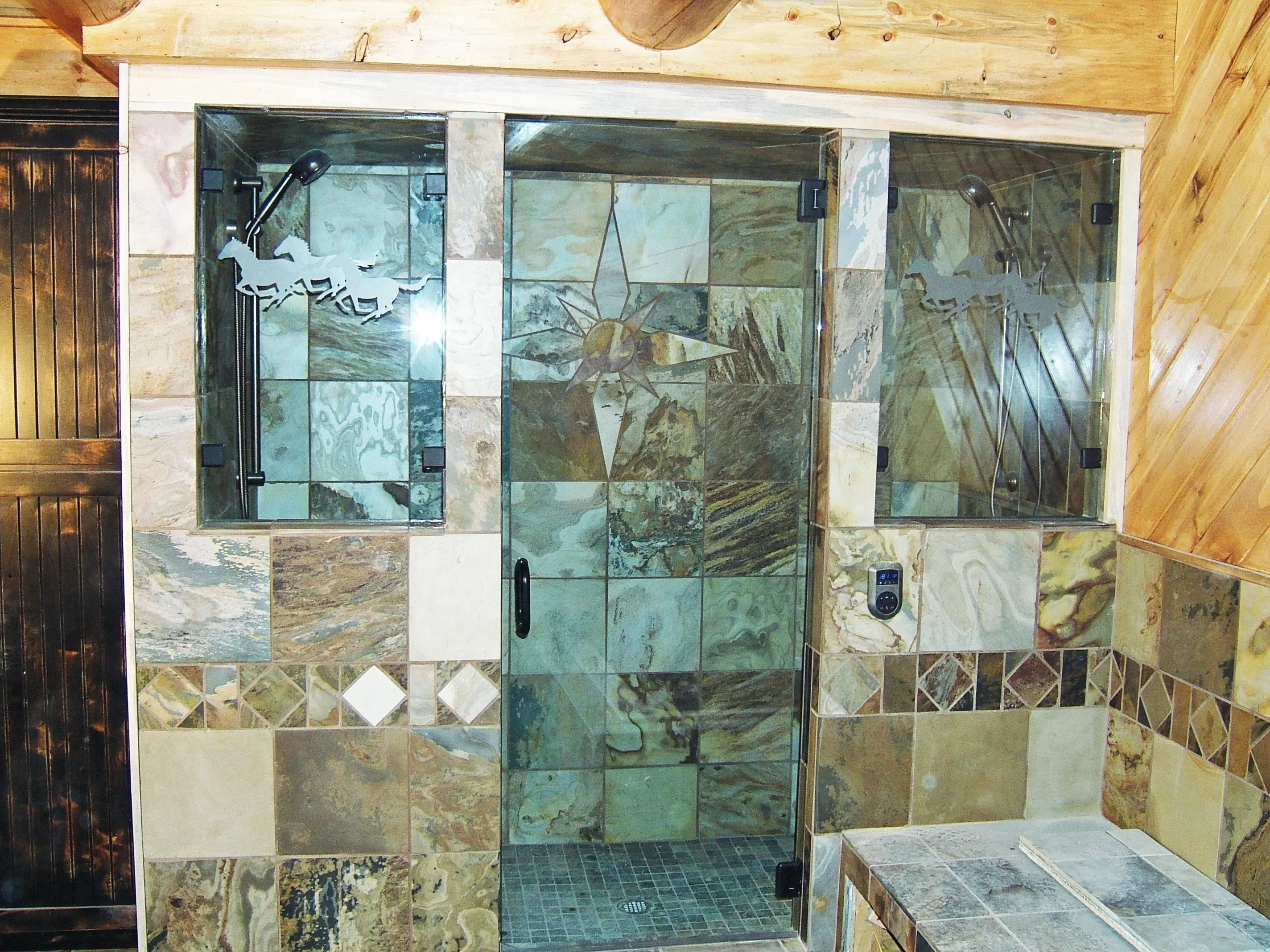 Frameless shower enclosure with artistic etched glass panels and mixed stone tile surround