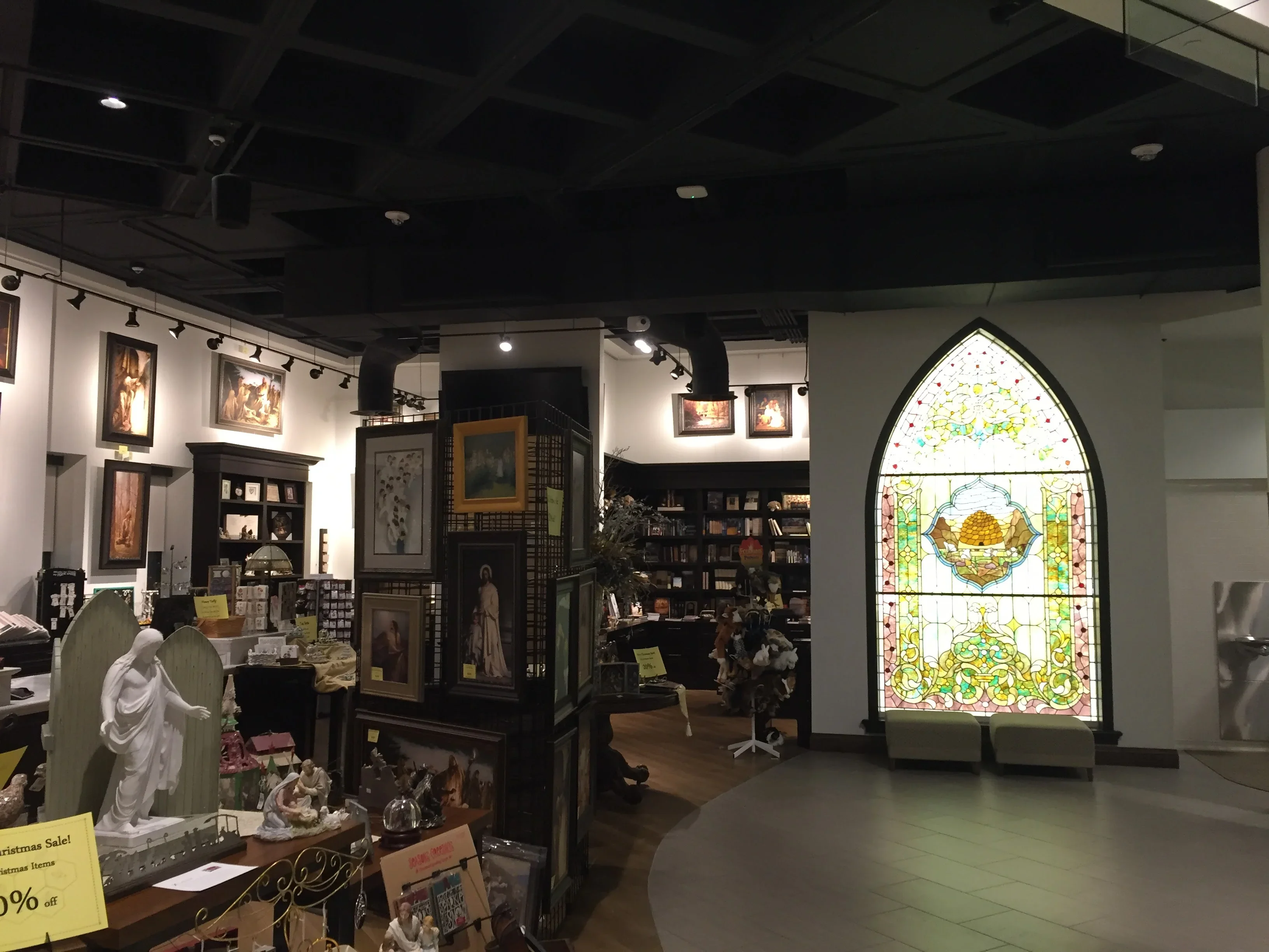 Arched stained glass window with religious motif and ornamental gold and green patterns