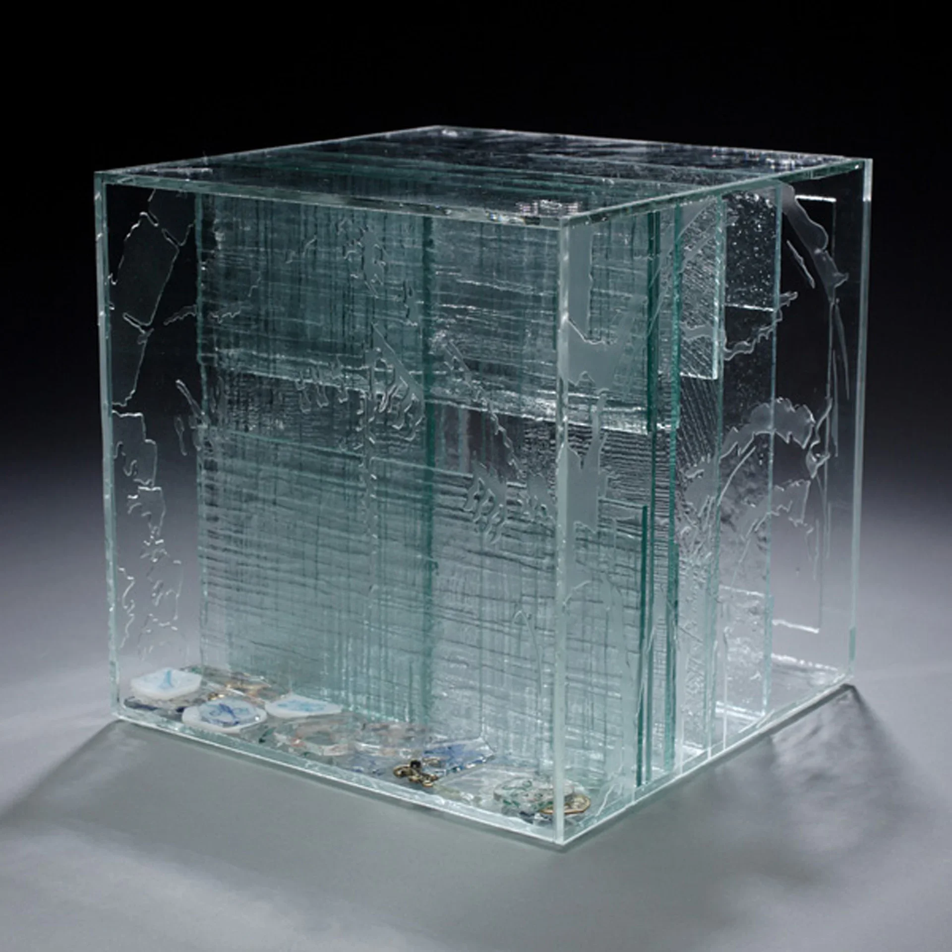 Etched glass display case with topographic designs and brass hardware on gray background