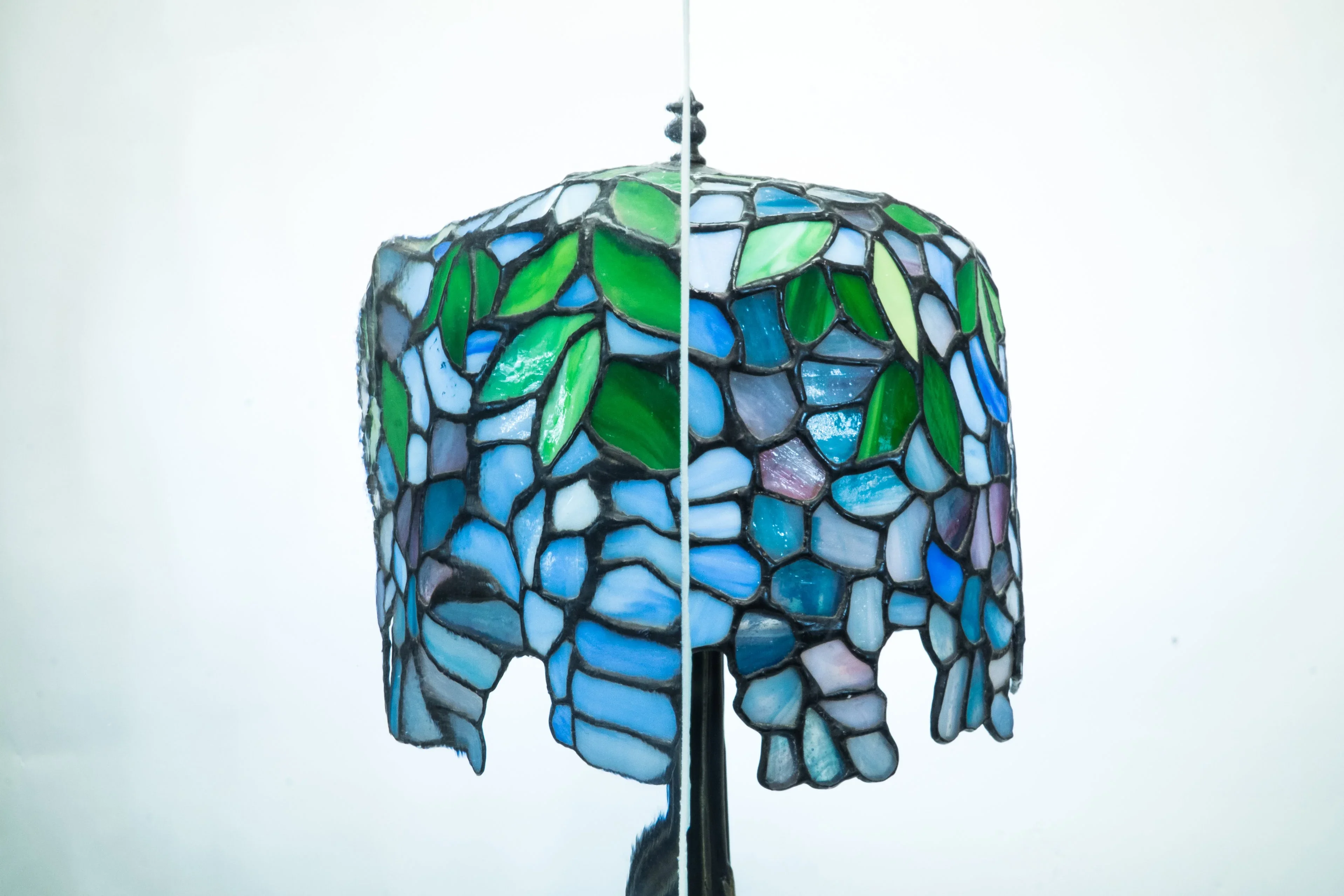 Stained glass pendant with blue and green mosaic pattern and decorative leaf details