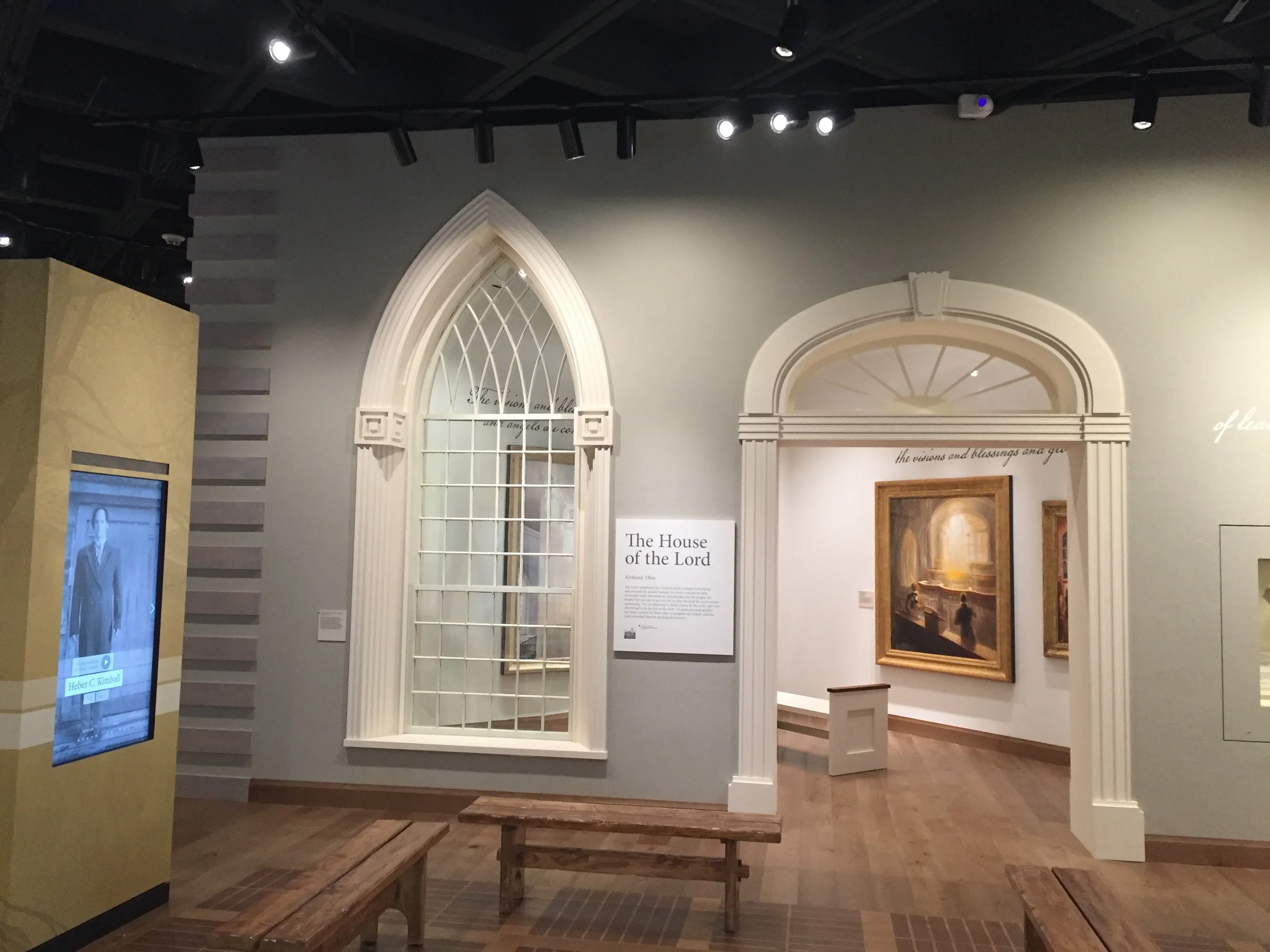 Gothic arched leaded glass window with white trim in museum gallery setting