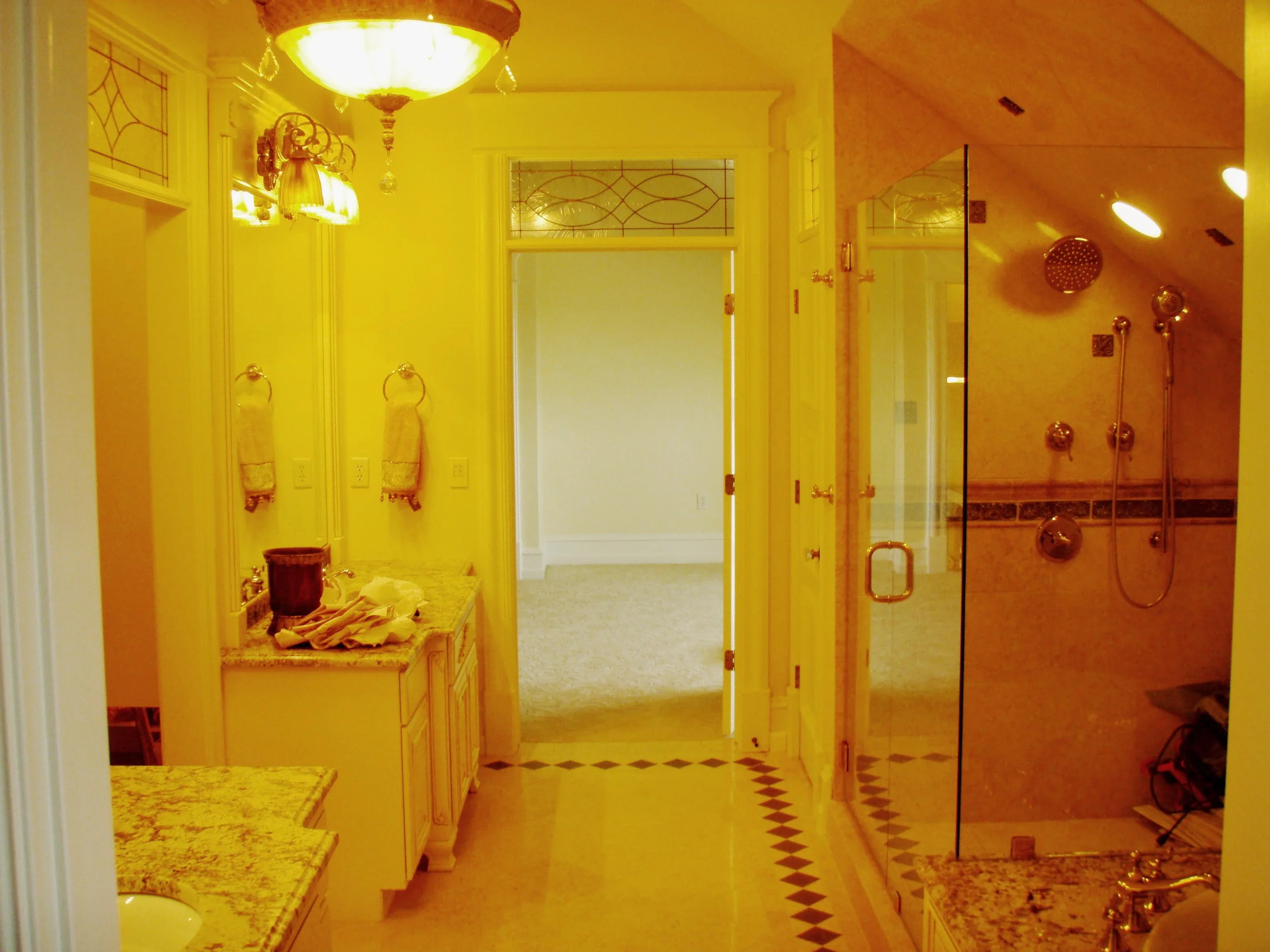 Frameless glass shower enclosure with brass fixtures and rainfall showerhead in luxury bathroom