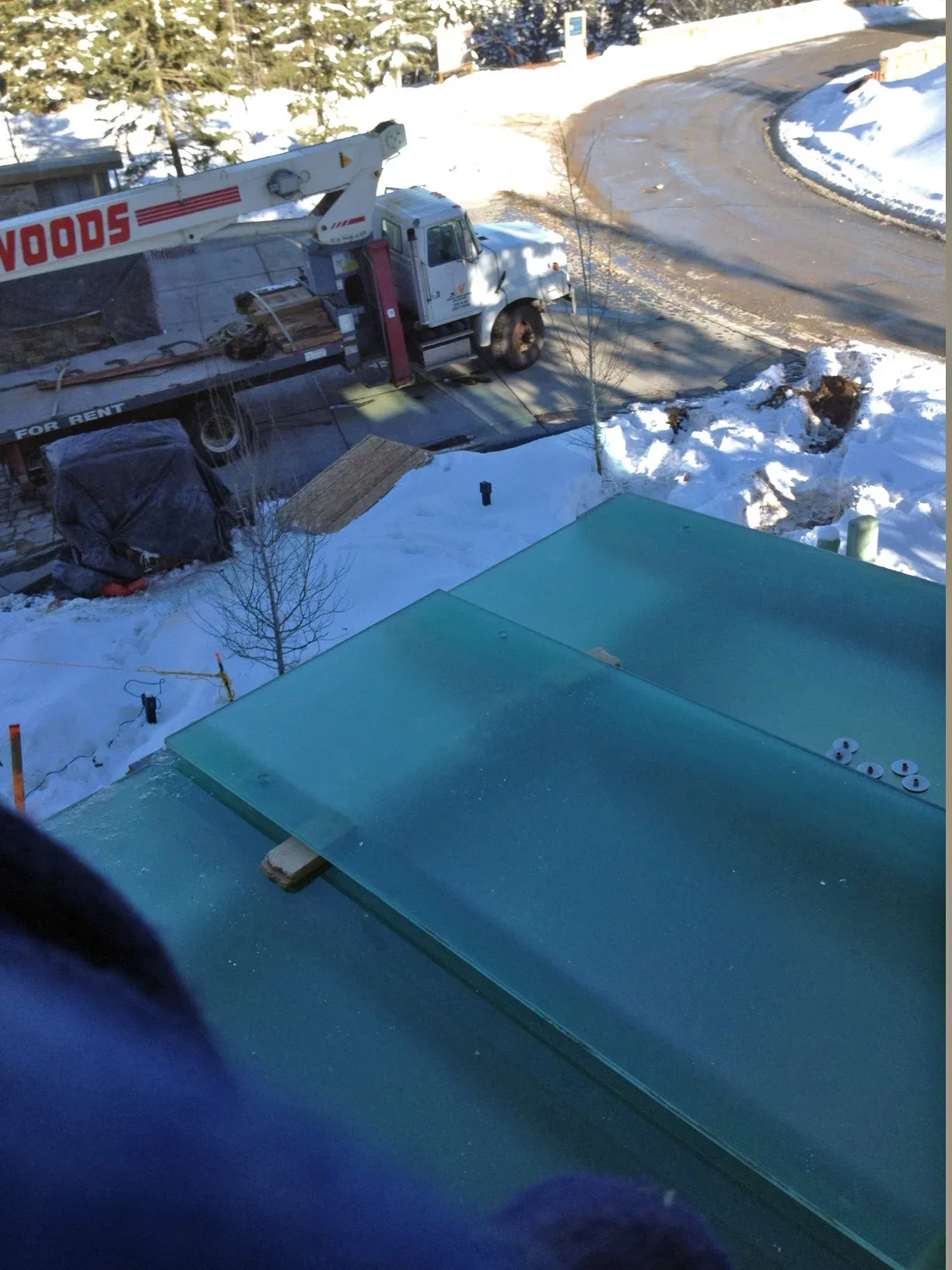 Glass panel installation on residential roof with delivery truck in snowy mountain setting