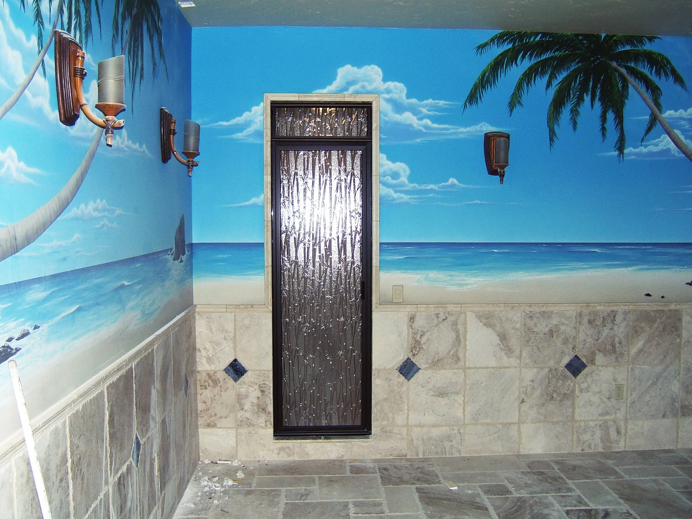 Black-framed shower door with bamboo-textured glass in tropical bathroom with beach mural