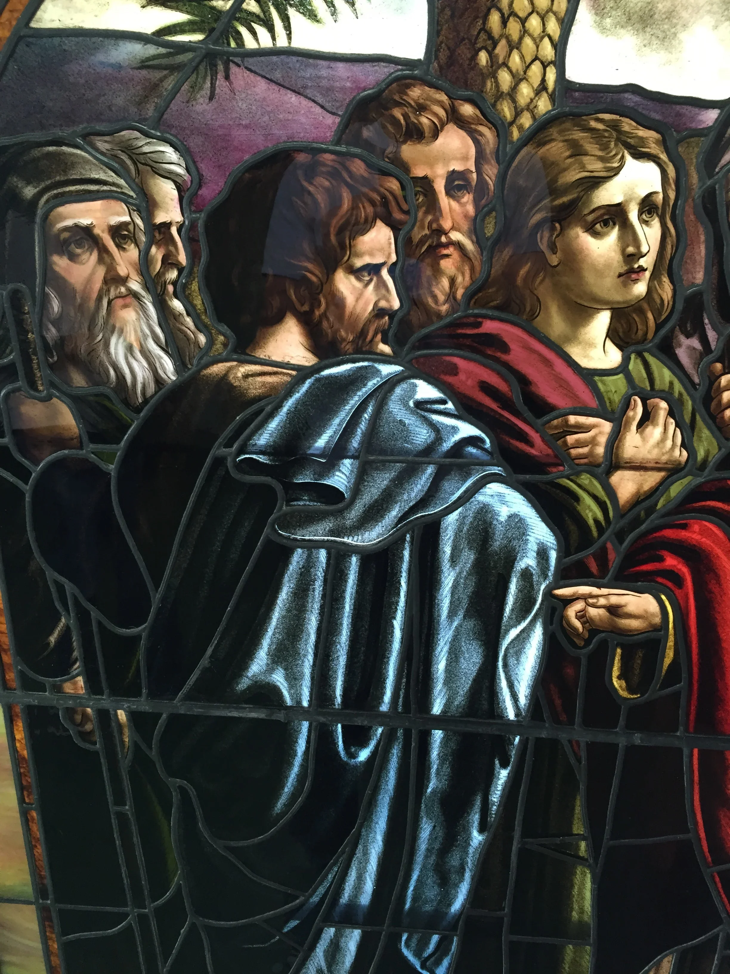 Stained glass window with five religious figures in robes, lead-came design with blue, red, and gold tones